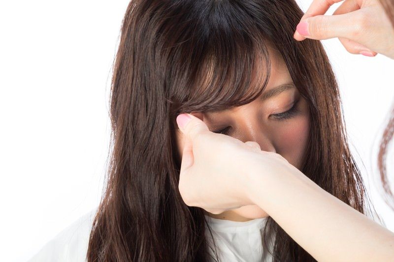 スタイリストが指で前髪をはさみ、長さを確かめている手元(モデル)