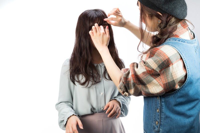 スタイリストが向かい合って、相手の前髪を指で整えている様子(モデル)