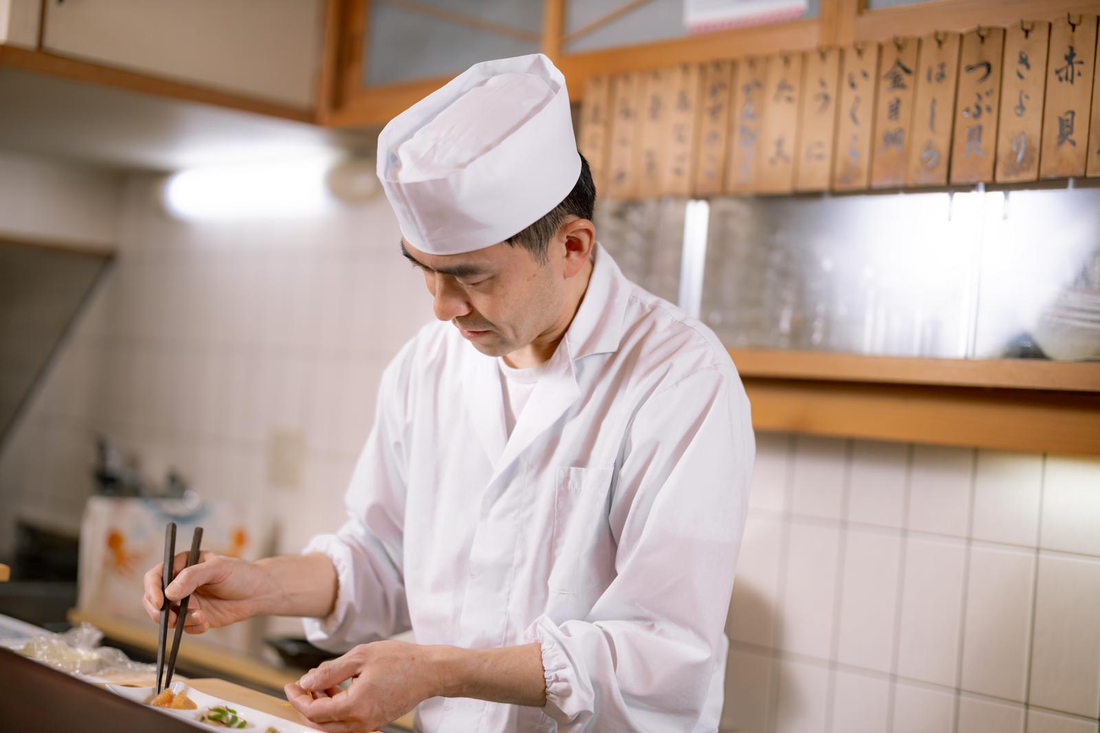 箸で小皿に料理を盛り付ける手元