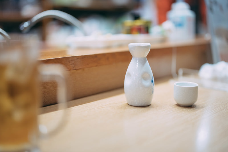 木のカウンターに置いた白い徳利とお猪口