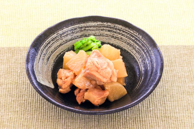 黒い鉢に盛った鶏肉と大根の煮物