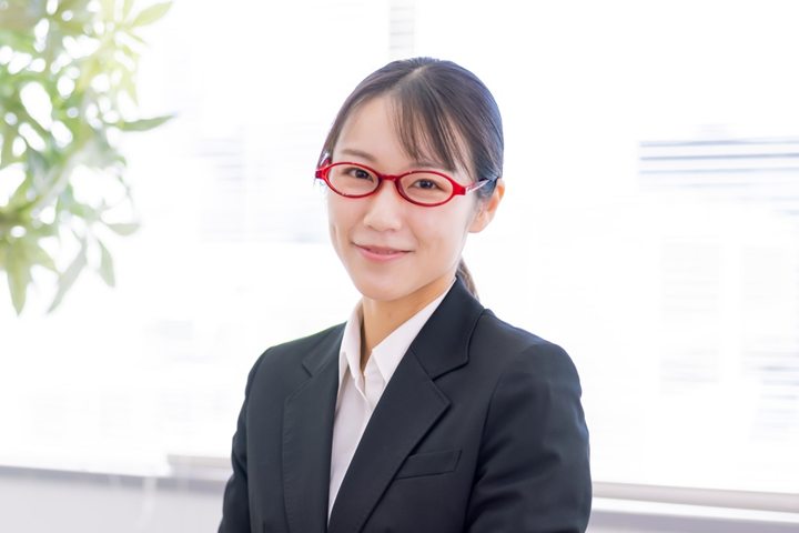 窓辺の机で、こちらを向いてほほえむ塾長(モデル)