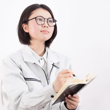 眼鏡をかけた現場担当が、手帳にメモを取っている(モデル)