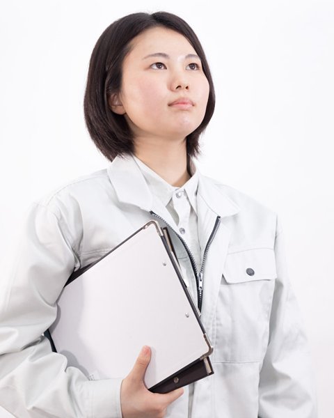 現場担当のイメージ写真。グレーの作業着で書類のファイルを抱える女性(モデル)