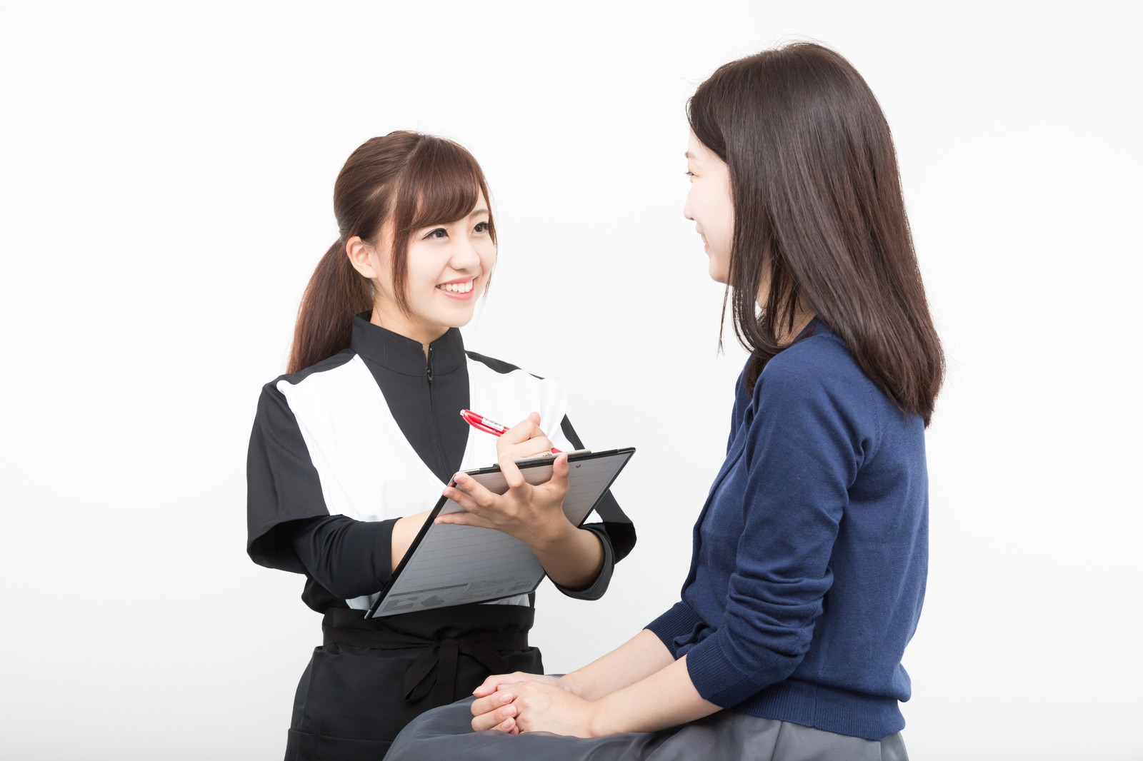 施術者がクリップボードを手に、向かい合う方のお話を伺っている様子(モデル)